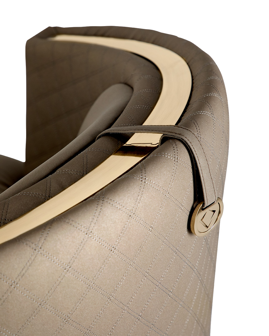 /storage/Luxury brass-accented modern lounge armchair with quilted padded fabric and smooth curves, combining comfort and elegance