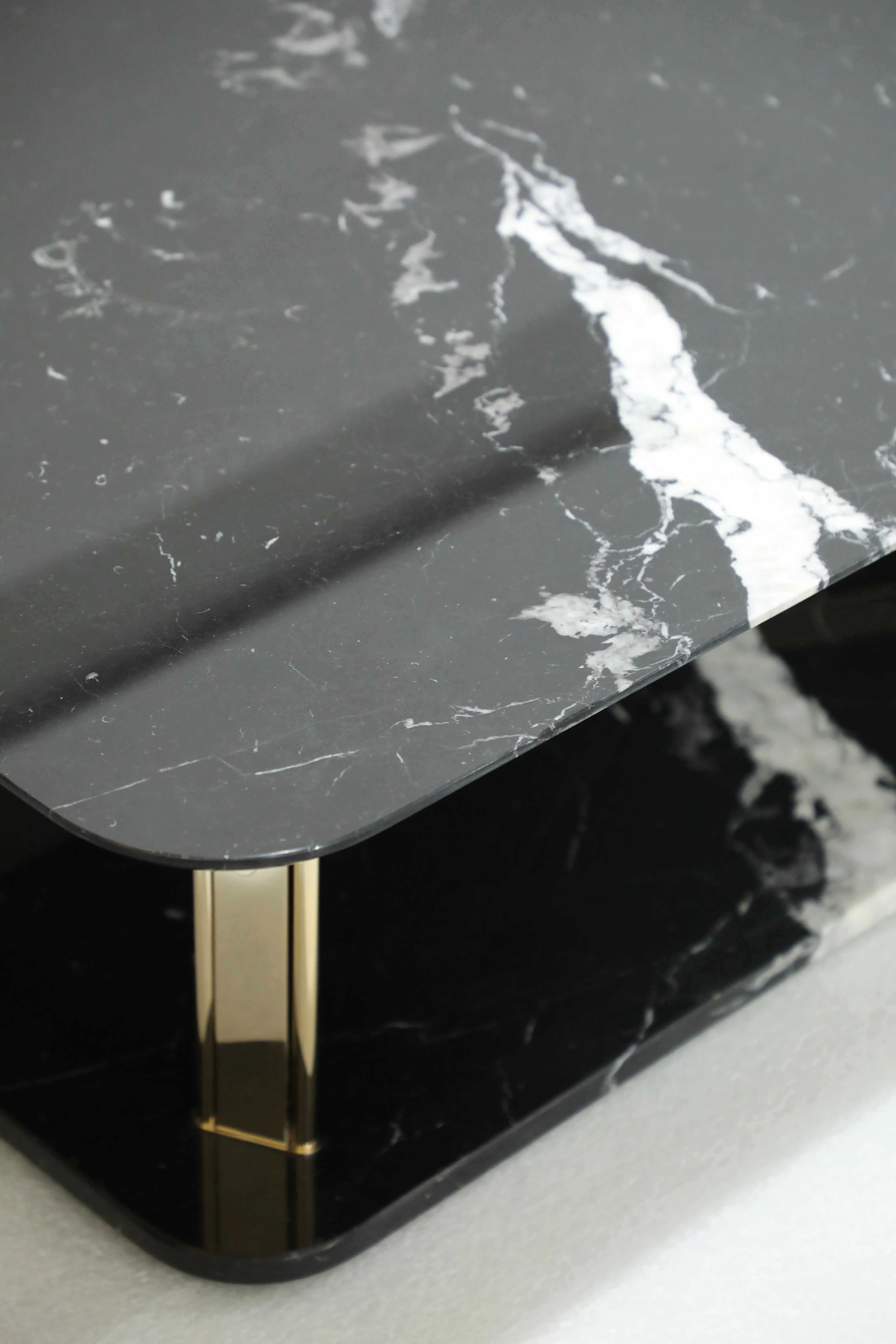 /storage/Luxury brass and marble center table with geometric columns, blending modern elegance and bold design for a refined, opulent living space.