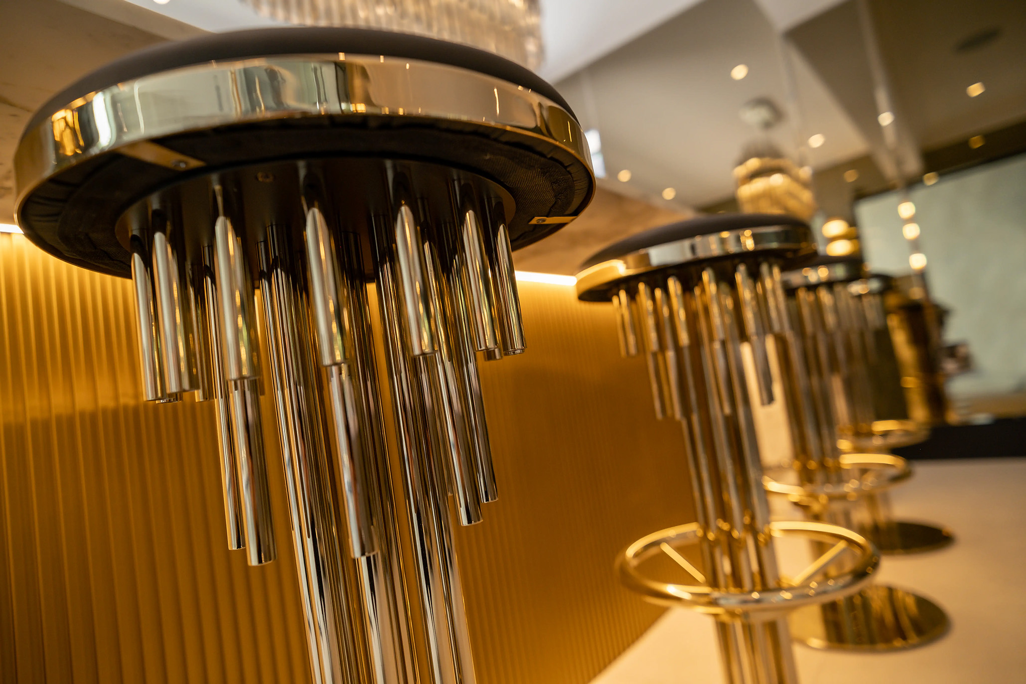 Projection Bar Stools in brass adding sculptural flair to a modern home bar