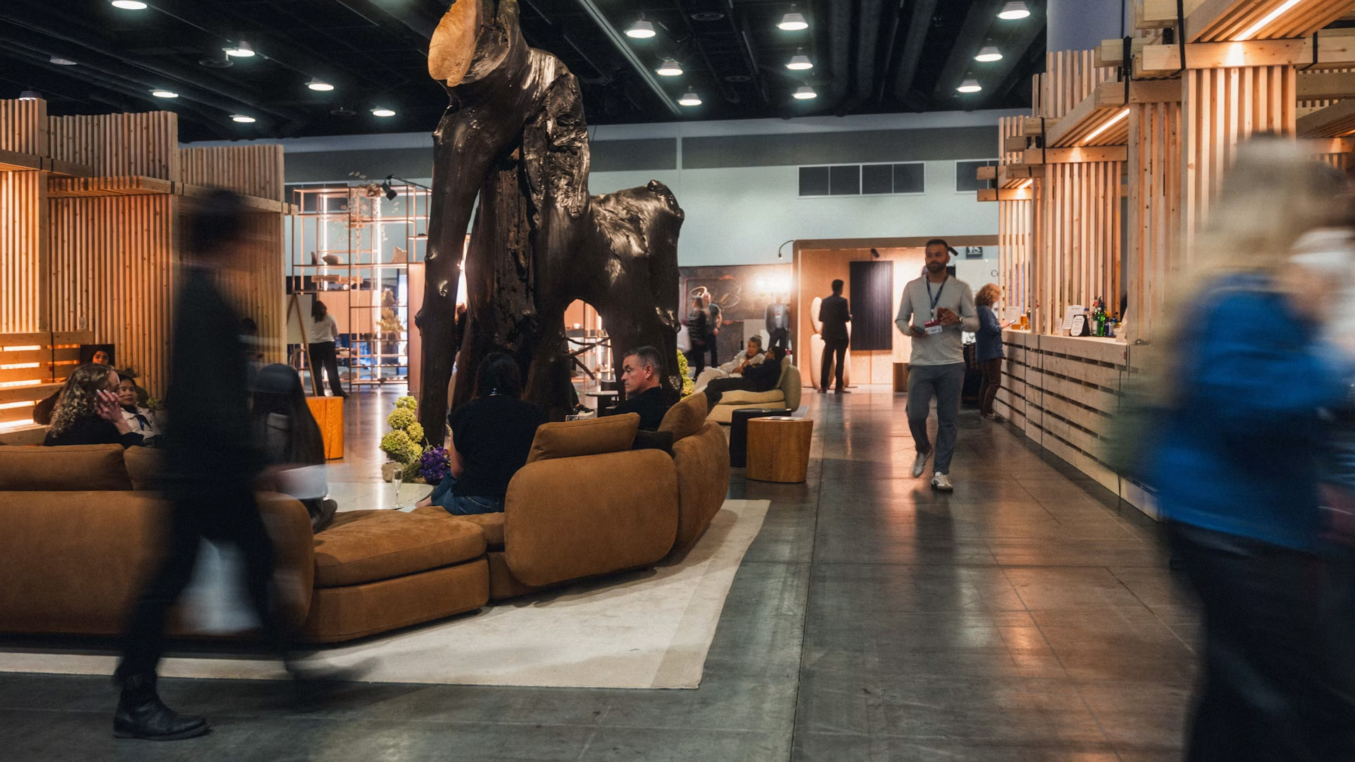 IDS Vancouver exhibition lounge with contemporary furniture, timber structures and visitors exploring the design show.