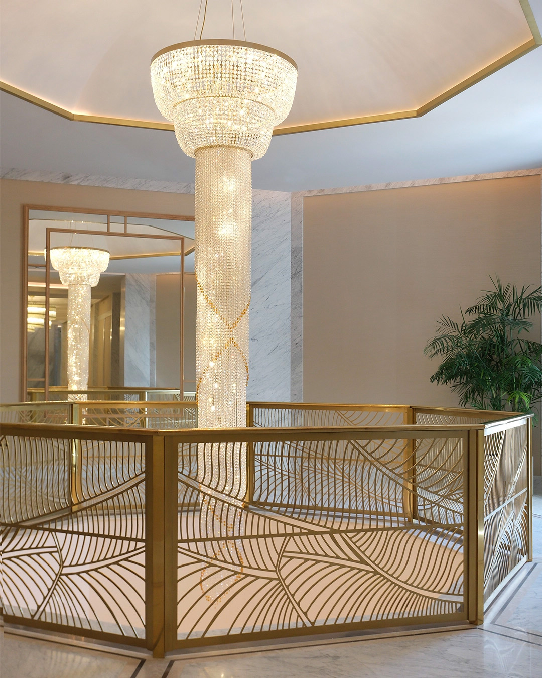 Hotel hall with stairs and a large bespoke chandelier in the middle of a wellness center, celebrating interior design collaborations in 2025.