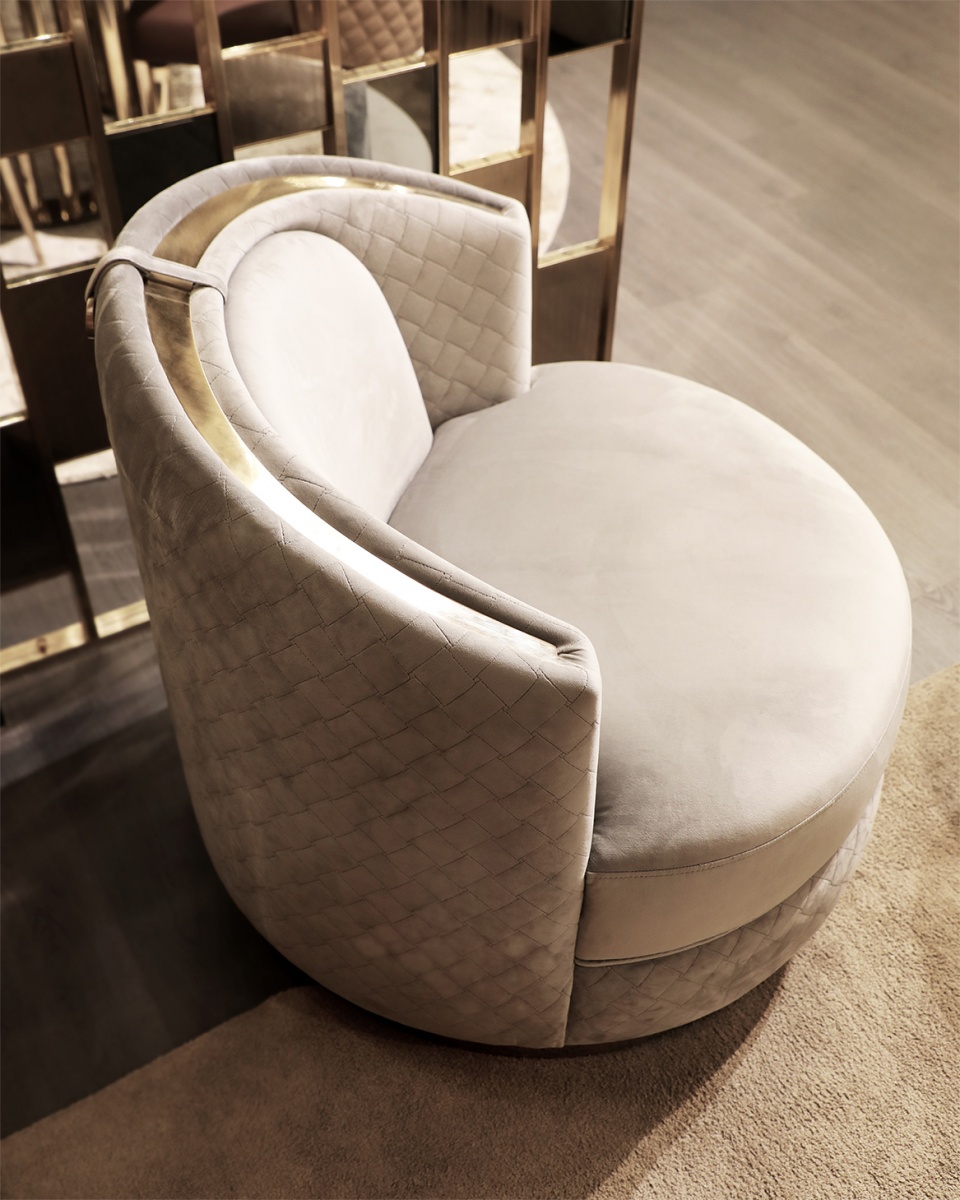 /storage/Luxury brass-accented modern lounge armchair with quilted padded fabric and smooth curves, combining comfort and elegance