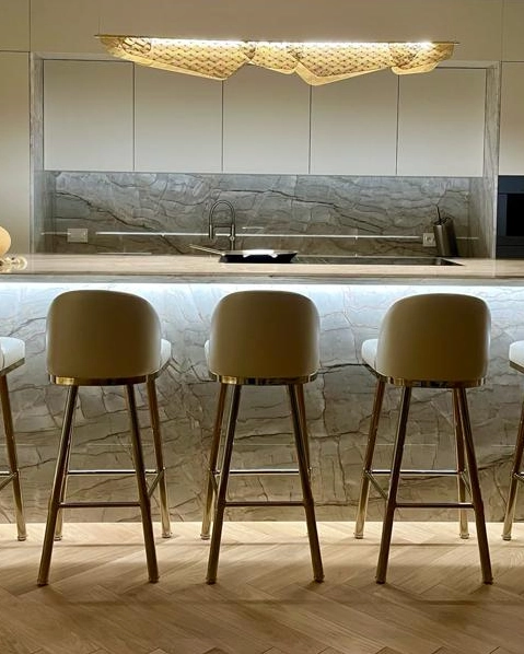 /storage/Luxury brass bar chair with gold-plated legs, black nickel accents, and curved upholstered body, blending Art Deco style with modern femininity.