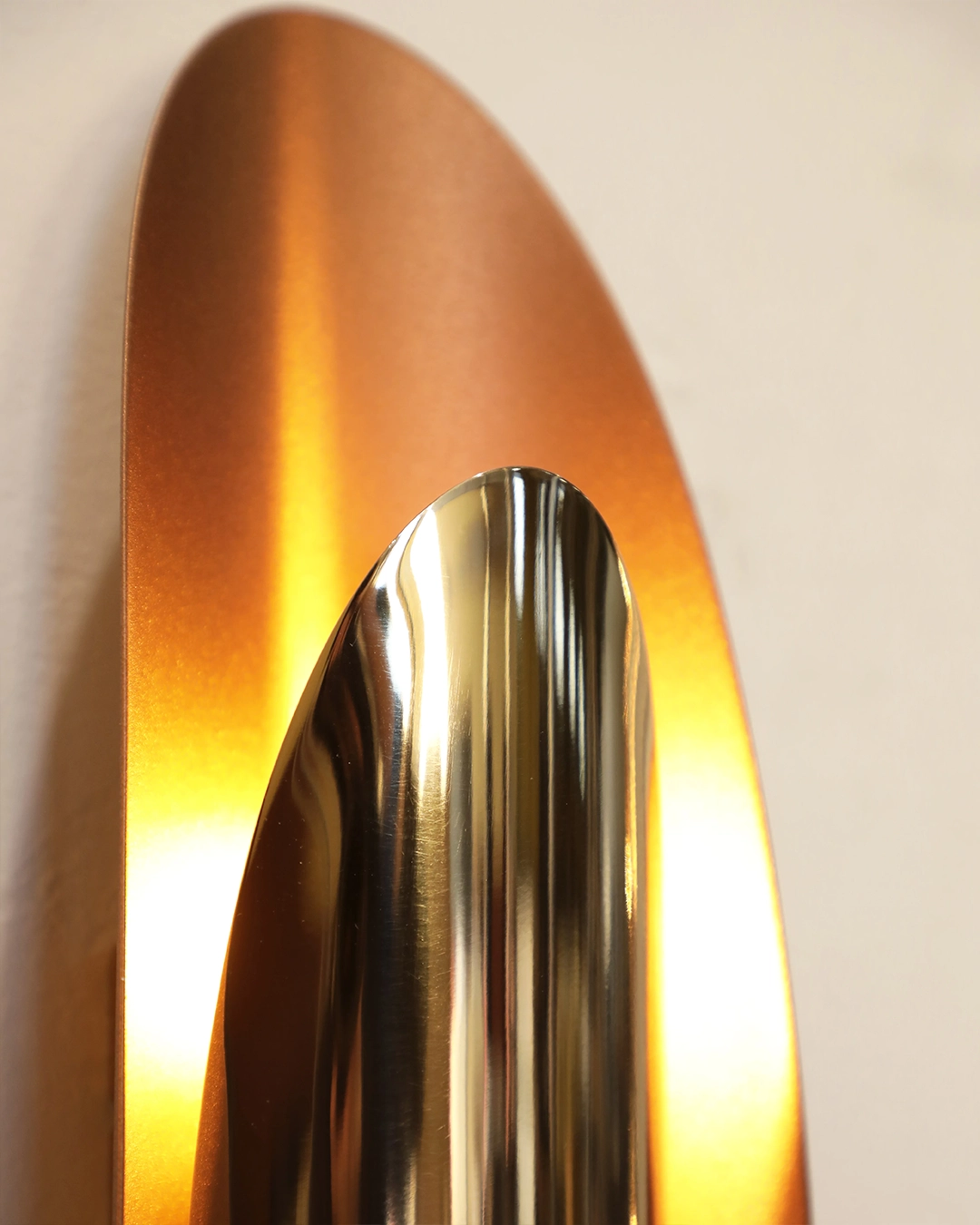 /storage/Luxury brass Radiance wall light with oval aluminum form, available in copper or white finish, creating a warm modern glow.