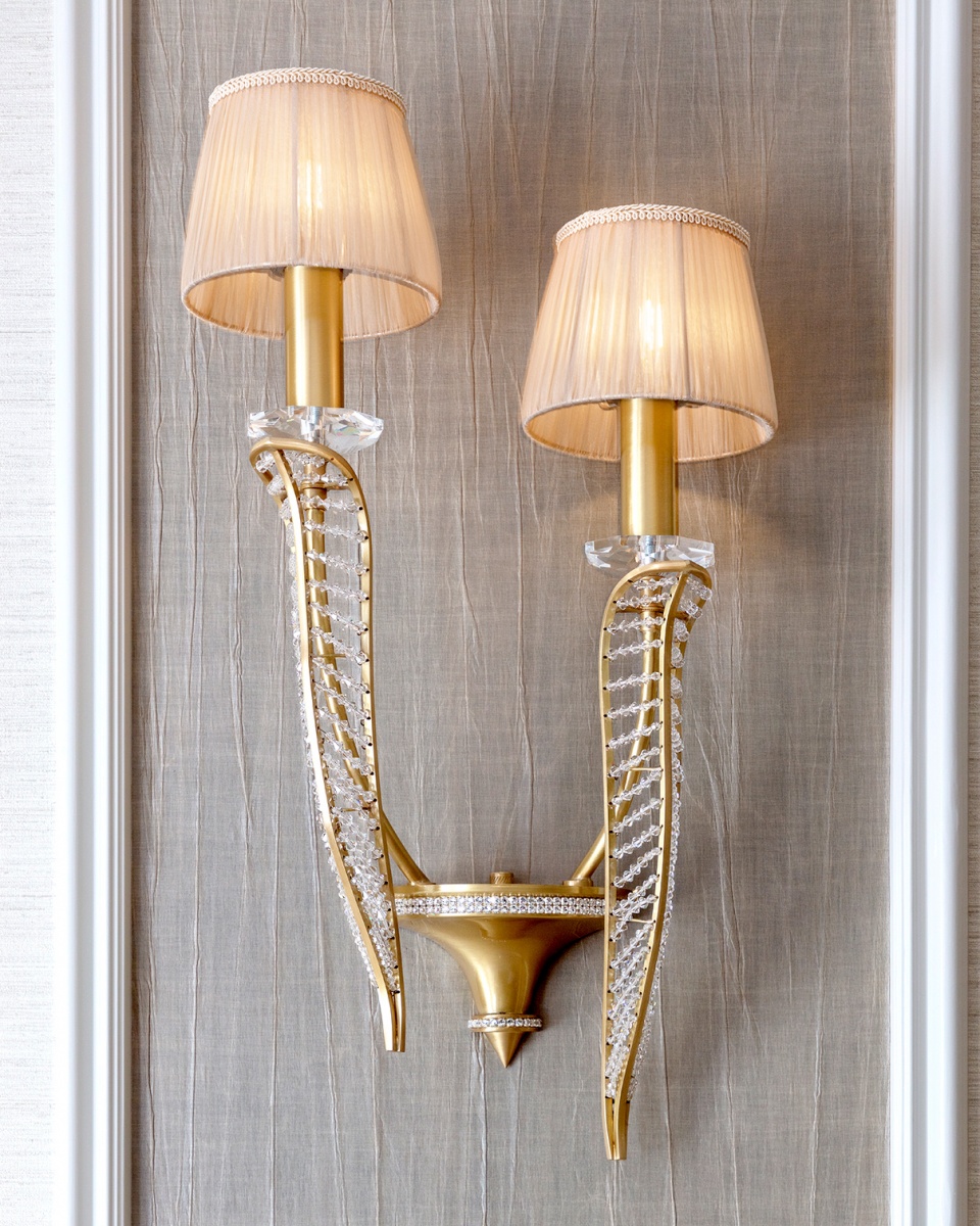 A vintage-inspired brass chandelier with a sleek, polished finish and intricate crystal details, hanging in an elegant, antique-styled room.