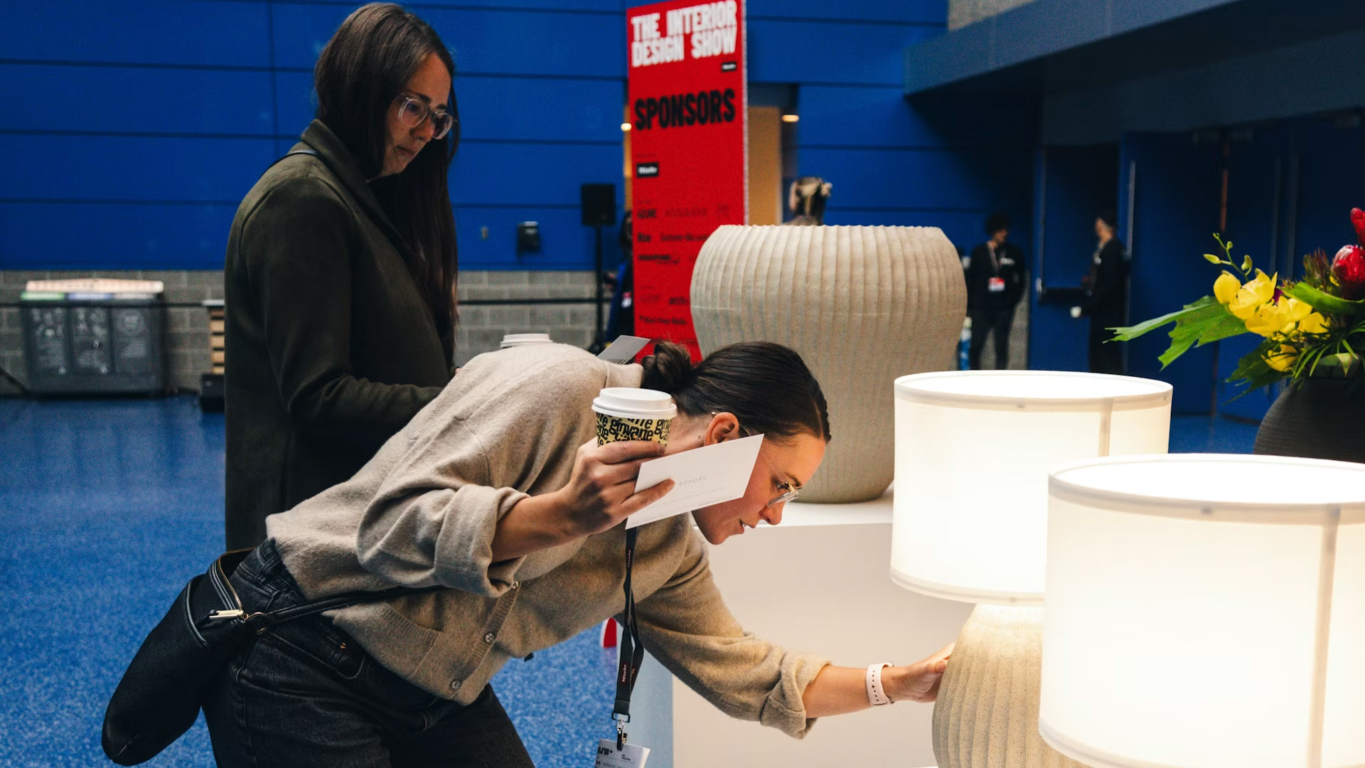 IDS Vancouver visitors examining contemporary lamps and decorative design pieces at the exhibition.