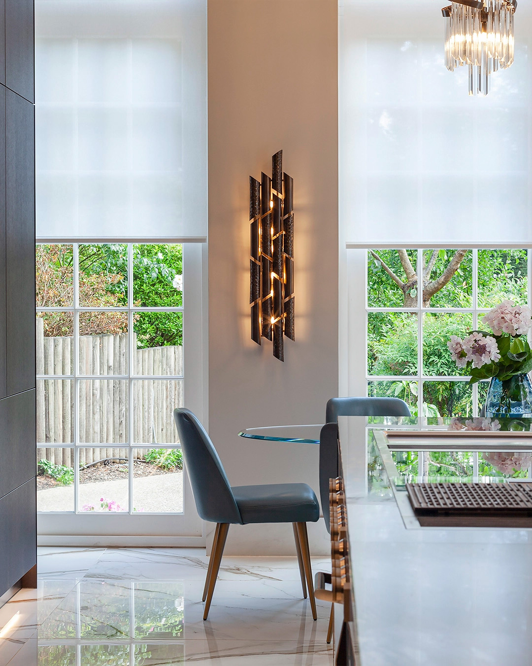Corner featuring a Castro wall light centered between two windows, with a chair and table on the right, highlighting interior design collaborations in 2025.
